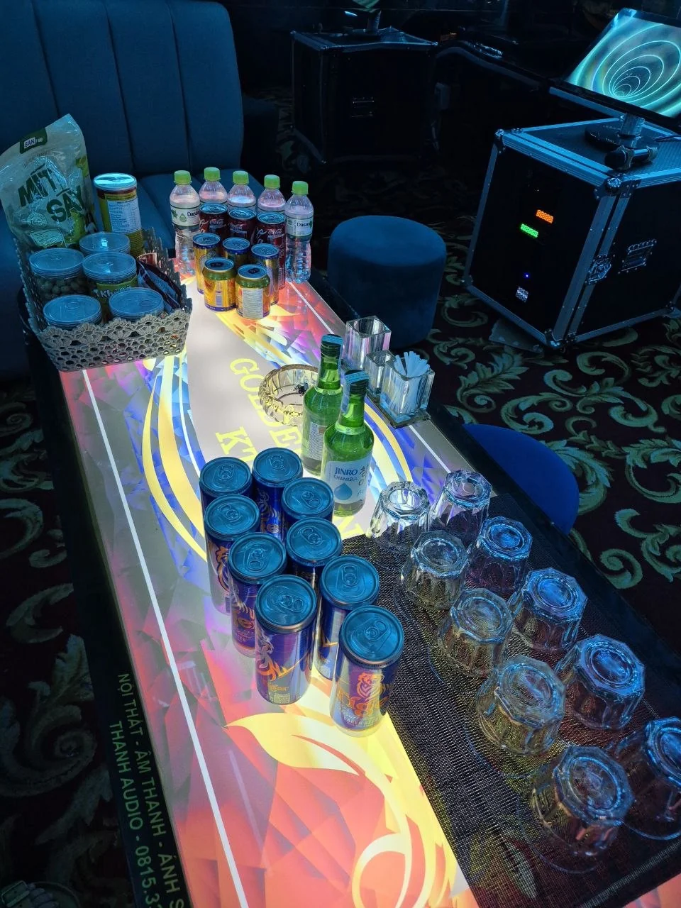 나트랑 골든싱 가라오케 KTV 로고가 비치는 LED 테이블 위 타이거 맥주 캔·진로 소주·생수·견과류 바구니와 잔