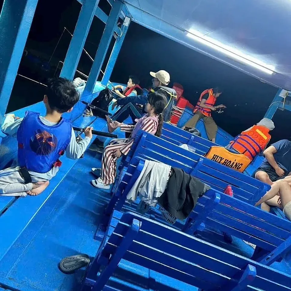 나트랑 오징어 낚시 투어 야간 선상 — 파란 벤치에 앉아 낚싯대를 드리운 손님들