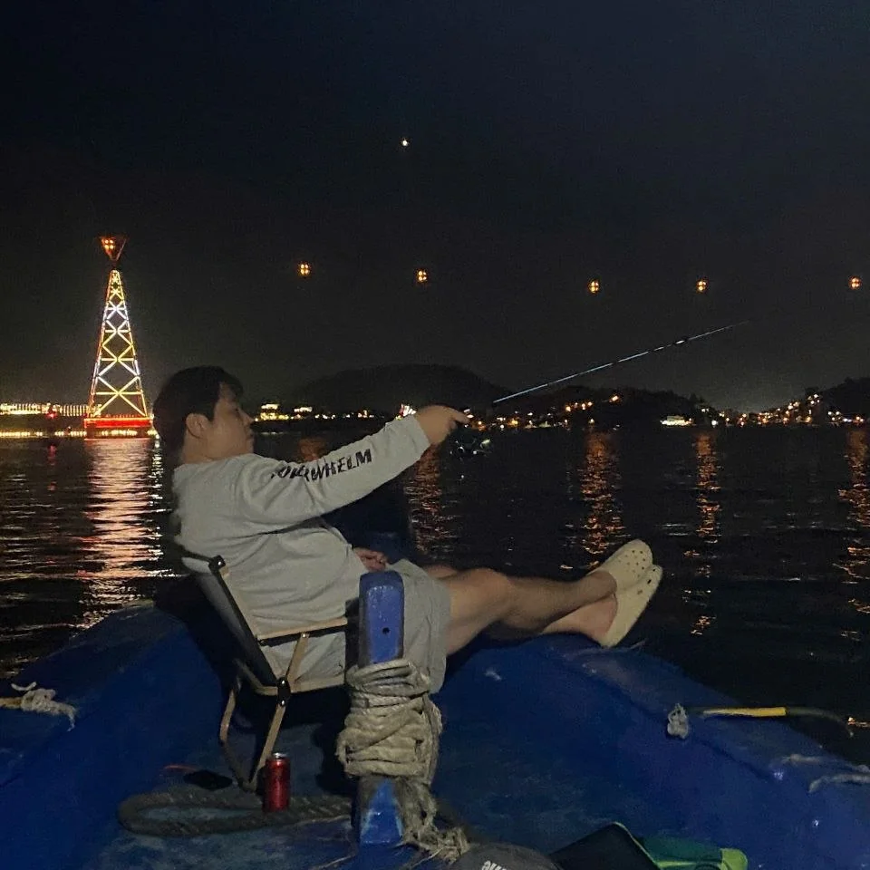 나트랑 오징어 낚시 투어 — 레인보우 타워 야경을 바라보며 선상 의자에 앉아 낚시하는 손님